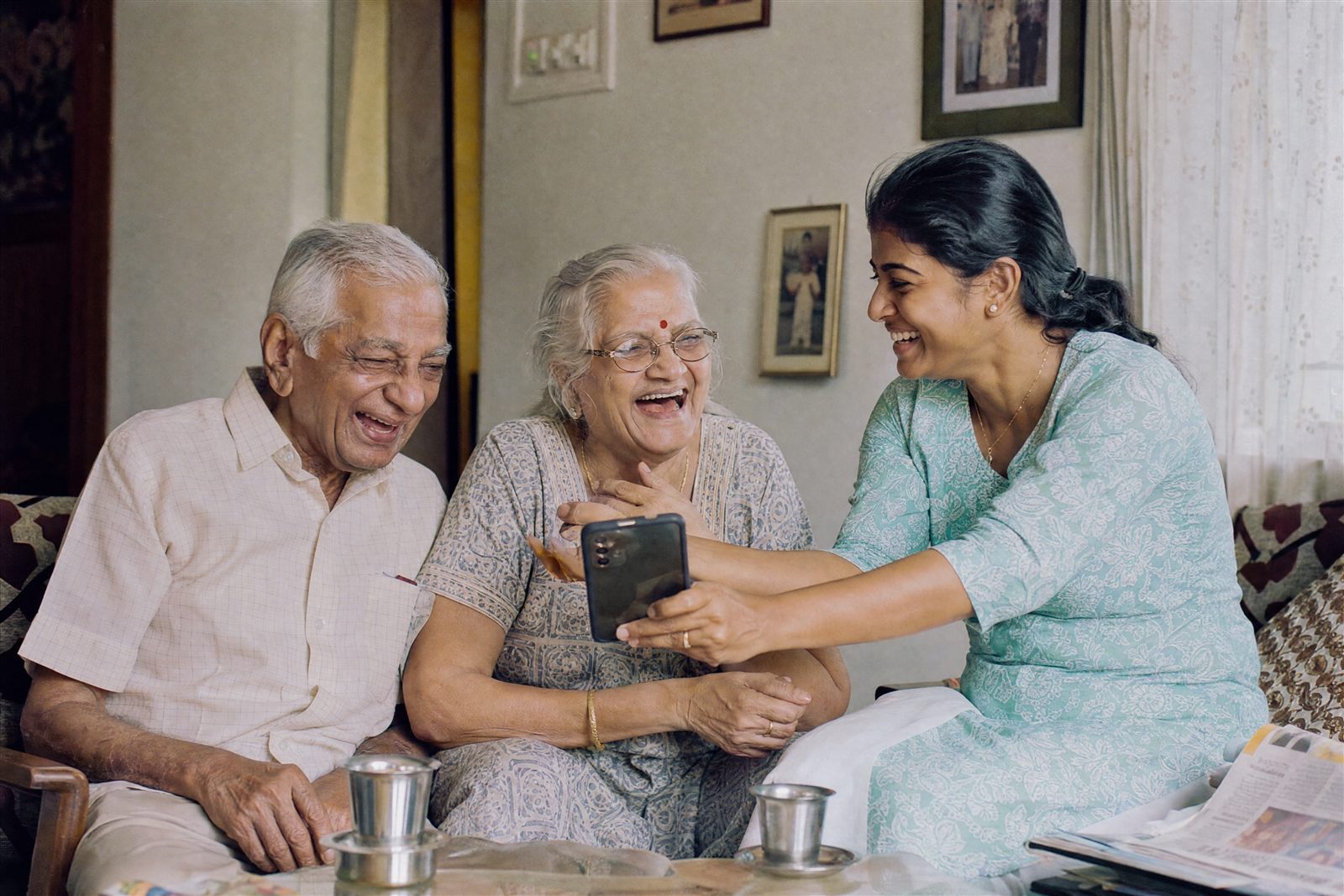Elderly couple laughing over morning coffee with their companion caregiver