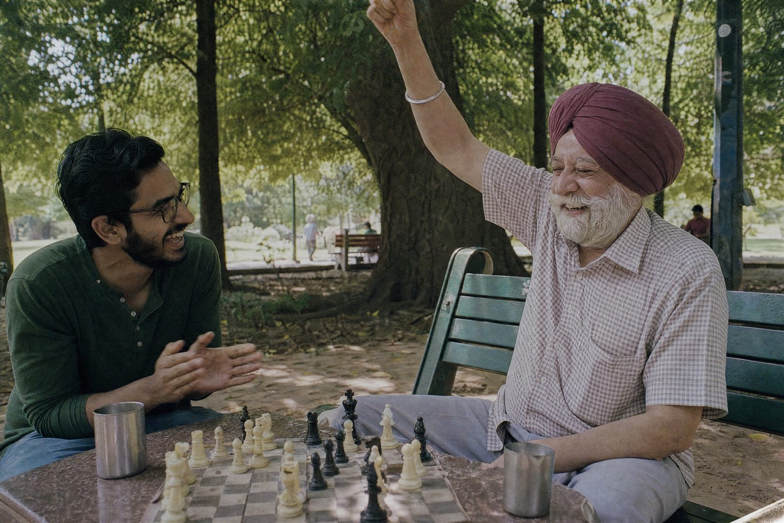 Elderly gentleman celebrating a chess win with his young companion in a park